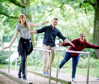 Drei Personen an einer Sinnenstation im Kurpark von Bad Laer 